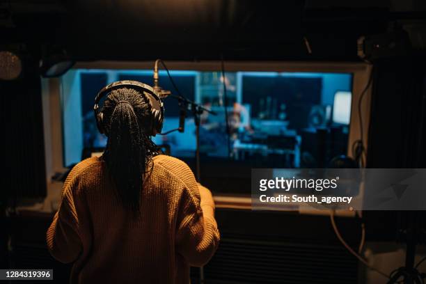 male sound engineer listening female singer singing into microphone in recording studio - sound producer stock pictures, royalty-free photos & images