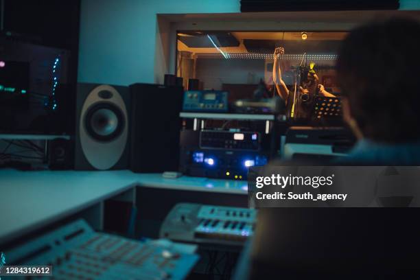 ingeniero de sonido masculino escuchando cantante punker masculino cantando en el micrófono en el estudio de grabación - micrófono de condensador fotografías e imágenes de stock