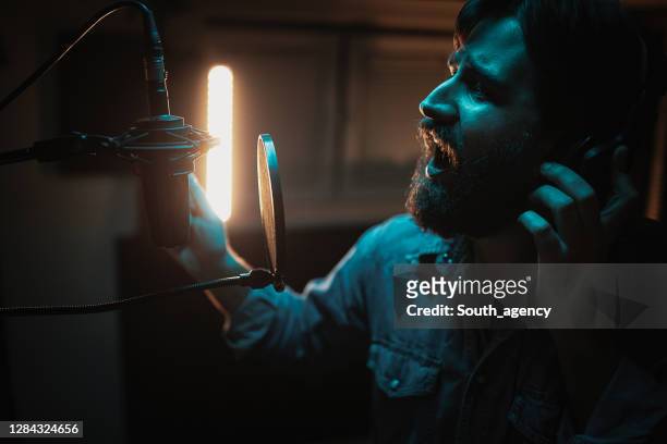 one male singer recording song in music studio - country and western music stock pictures, royalty-free photos & images