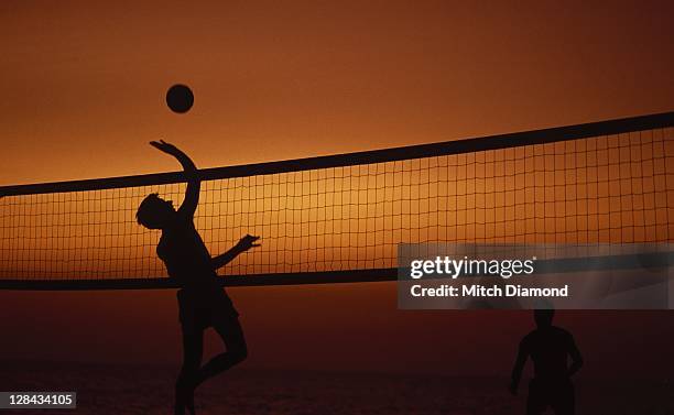 silhouette of two men playing volleyball - juego de voleibol de playa fotografías e imágenes de stock