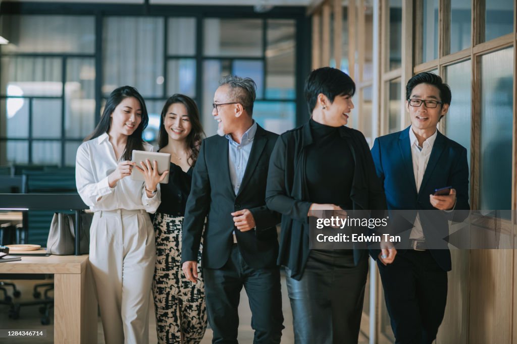 Group of asian chinese successful office management team having discussion while walking toward camera