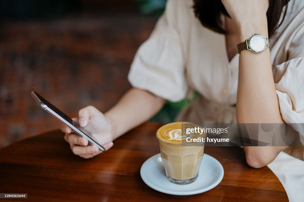 Een Aziatische Chinese vrouw die smartphone in café gebruikt