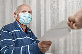 senior man wearing protective face mask taking paper sheet with recipe from doctor hand