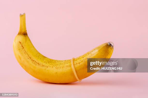 condom on a ripe yellow banana - condoms imagens e fotografias de stock