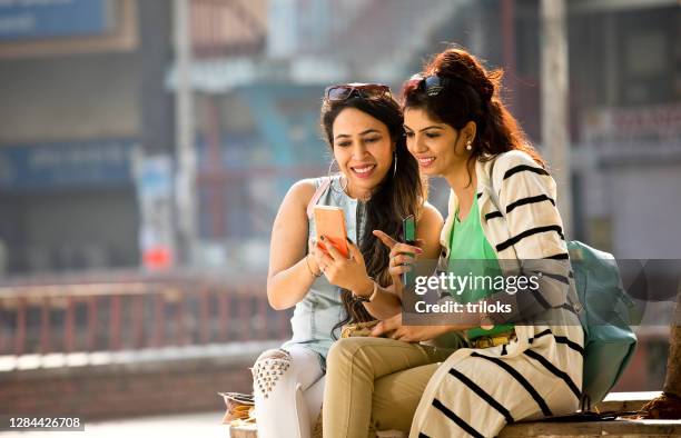 women enjoying funny video on mobile phone - two women stock pictures, royalty-free photos & images