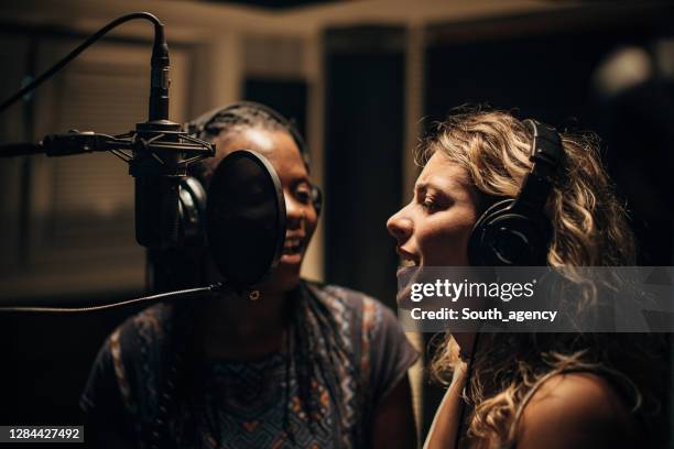 two female singers singing into microphone in recording studio together - duet stock pictures, royalty-free photos & images