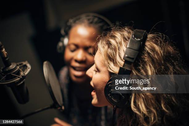 twee vrouwelijke singers die een duet in opnamestudio samen zingen - duet stockfoto's en -beelden