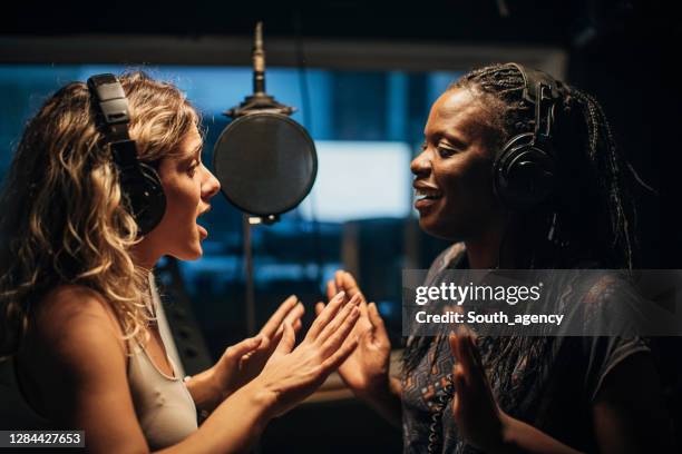 two female singers singing a duet in recording studio together - soloist stock pictures, royalty-free photos & images