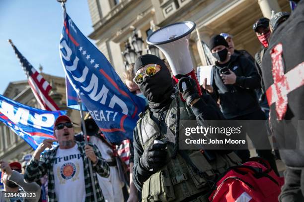 Counter-protesters walk though a group of Trump supporters during a demonstration over election ballot counting outside the Michigan State Capitol...