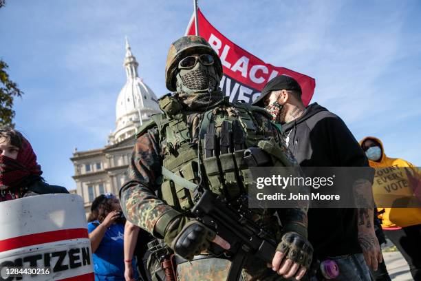 Counter-protesters, some wearing camouflage and carrying Black Lives Matter flags walk past a group of Trump supporters during a demonstration over...