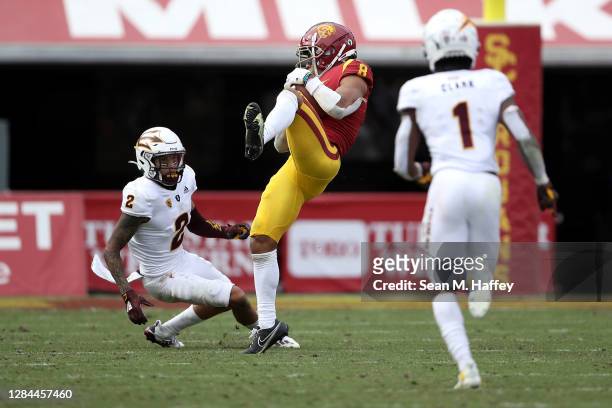 Amon-Ra St. Brown of the USC Trojans catches a pass as DeAndre Pierce and Jordan Clark of the Arizona State Sun Devils defend during the second half...