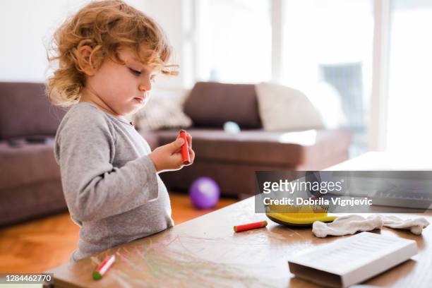 toddler standing in the living room and holding wax color - baby paint hand imagens e fotografias de stock