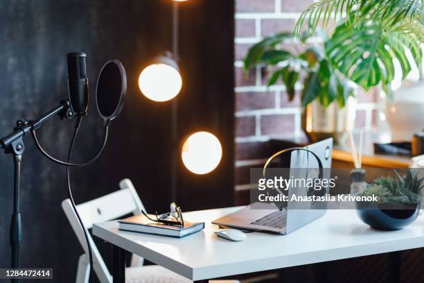 podcast streaming at home. audio studio with laptop, microphone with pop filter and headphones on white table against black wall with warm lights. blogger concept. - best sound editing bildbanksfoton och bilder
