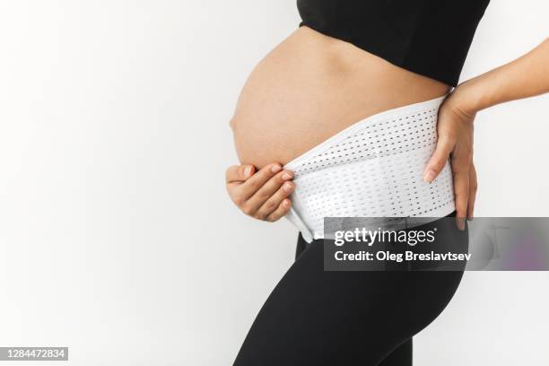 pregnant woman with naked abdomen in support bandage medical corset close-up. unrecognisable person. - orthopedic corset stock pictures, royalty-free photos & images