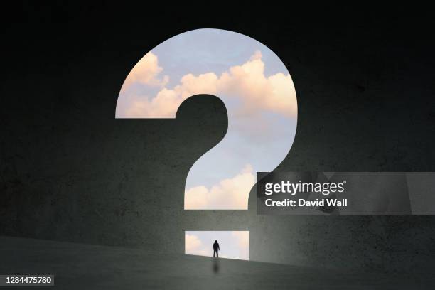a concept, of a man silhouetted against a question mark and clouds - answering stock-fotos und bilder