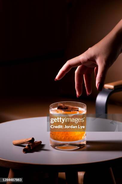 woman reaching for a whisky glass - whisky cocktails stock pictures, royalty-free photos & images