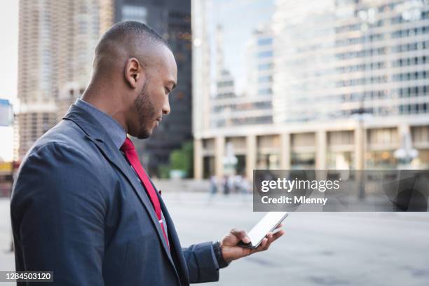 afroamerikanischer geschäftsmann bestellt taxi mit handy in chicago - businessman taxi stock-fotos und bilder