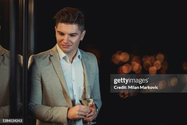 proud owner of a winery - a confident young businessman sitting outside drinking wine and enjoying a pleasant night - high society stock pictures, royalty-free photos & images