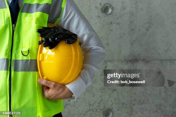 ritratto di operaio edile che tiene il casco giallo da vicino - abbigliamento antinfortunistico foto e immagini stock