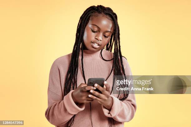 beautiful teenager using smartphone on yellow background - cute 15 year old girls stock pictures, royalty-free photos & images