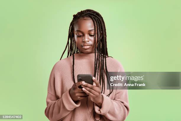 beautiful teenager using smartphone on green background - braided hairstyles for african american girls stock pictures, royalty-free photos & images