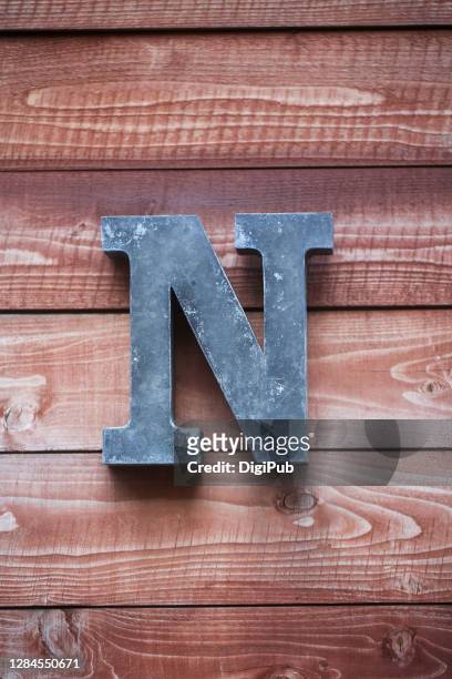 iron sheet 3d capital letter n on plank wall - n stock pictures, royalty-free photos & images