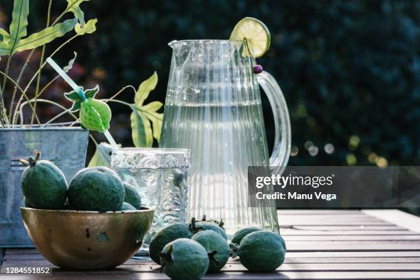 jug with lemonade and green guavas on a wooden table - stock photo - smaragdgroen stockfoto's en -beelden