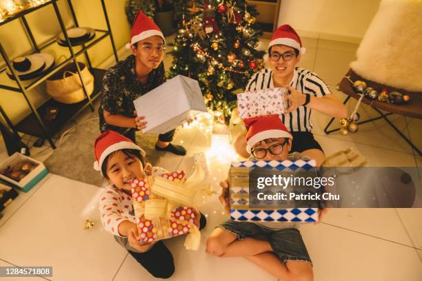 amici e fratelli cinesi asiatici che tengono regali guardando la macchina fotografica durante la celebrazione di natale - 12 17 mesi foto e immagini stock