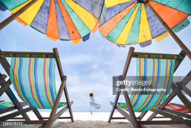 beautiful girl with colourful umbrellas and beach chair on white sand and clear blue sky on kai islands, phuket, thailand. - beach umbrella sand stock-fotos und bilder