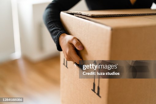 Woman carrying boxes into her new home Woman carrying boxes into her new home