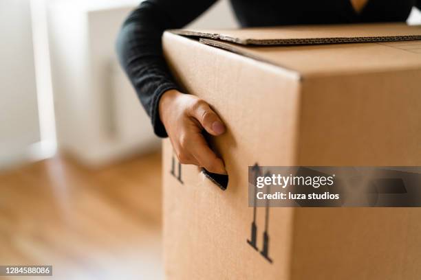 woman carrying boxes into her new home - package imagens e fotografias de stock