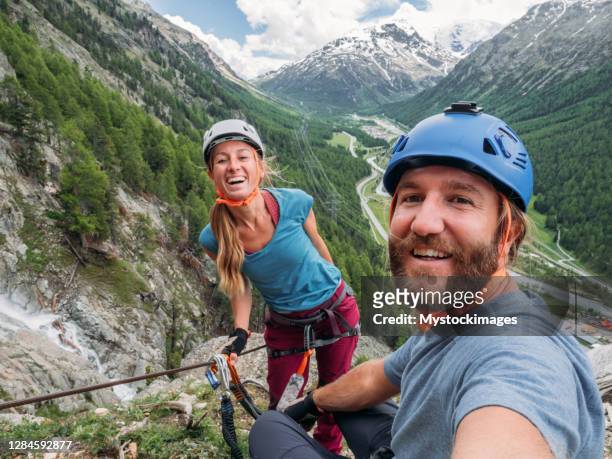 paar dat selfie op via ferrata neemt - team climbing up to mountain top stockfoto's en -beelden