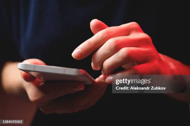 mobile phone in the hands of a girl. a young woman in a black t-shirt is holding a phone. an email fraudster sends a message. the work of a freelancer, businessman. - shooting crime foto e immagini stock