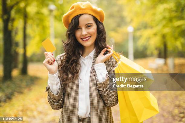 felice donna di moda che trasporta borse della spesa e in possesso di carta di credito - etichetta per regali foto e immagini stock