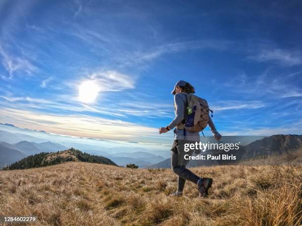 side view of a woman running downhill in carpathian mountains on the ukrainian-romanian border - discovery bags walking stock pictures, royalty-free photos & images