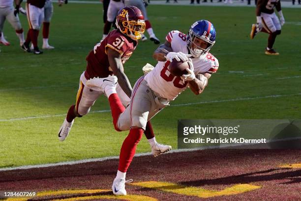 Evan Engram of the New York Giants scores a touchdown past Kamren Curl of the Washington Football Team in the second quarter at FedExField on...