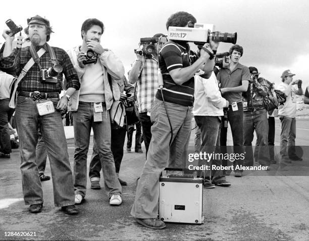 Photographers and TV videographers wait to take photographs of NASCAR cars and drivers during a practice session prior to the start of the 1980...