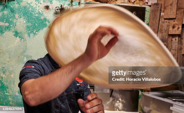 Chef Roberto Mezzapelle wears a protective mask as he tosses pizza dough in the air at "Refeitório Senhor Abel" restaurant the night before the...