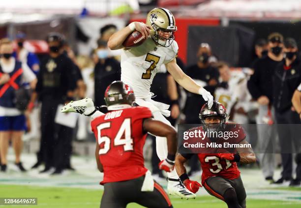 Taysom Hill of the New Orleans Saints attempts to hurdle Lavonte David and Antoine Winfield Jr. #31 of the Tampa Bay Buccaneers during the first half...