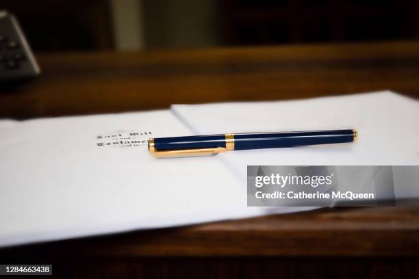last will & testament & other estate planning documents on wooden desk under pen - leichenbestatter stock-fotos und bilder