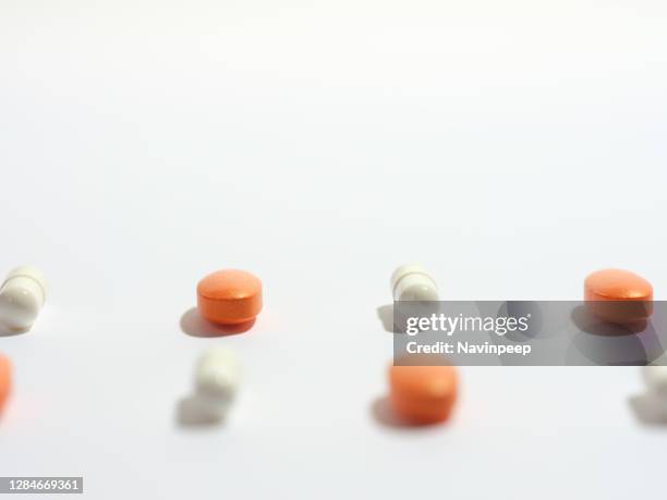 orange medicine pill and white capsule tablet lined up in a grid on white background - vitamin sachet stock pictures, royalty-free photos & images
