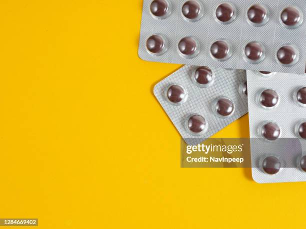 brown medicine tablet on yellow background - vitamin sachet stock pictures, royalty-free photos & images