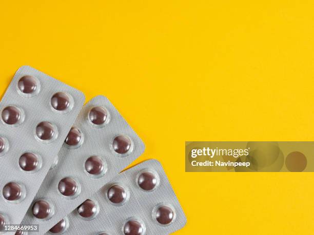 brown medicine tablet on yellow background - vitamin sachet stock pictures, royalty-free photos & images