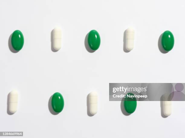 green medicine pill and white capsule tablet lined up in a grid on white background - vitamin sachet stock pictures, royalty-free photos & images