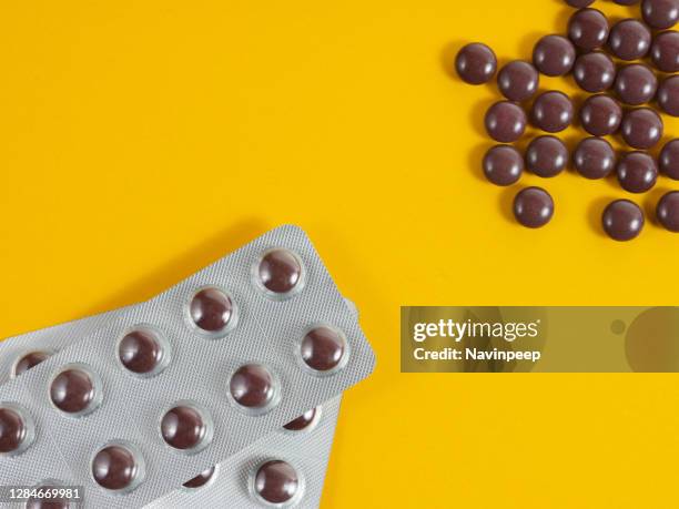 brown medicine tablet on yellow background - vitamin sachet stock pictures, royalty-free photos & images