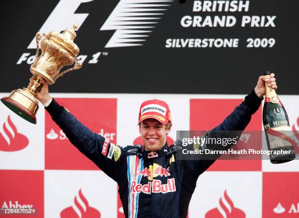 German Red Bull Racing Formula One driver Sebastian Vettel celebrates on the winners podium by raising the winners trophy and bottle of champagne...