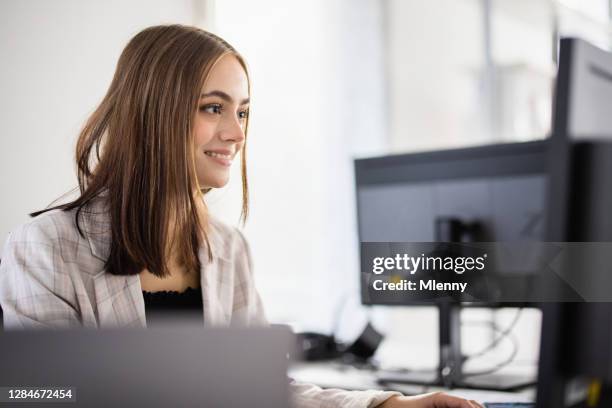 junge frau arbeitet im modernen büro am computer-schreibtisch - apprentice office stock-fotos und bilder