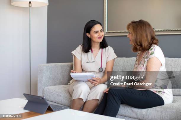 a female doctor visiting a senior woman at her home. - menopause stock pictures, royalty-free photos & images