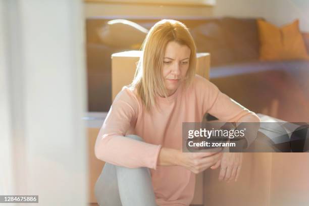 kvinna som sitter på golvet, lutad på en låda och sms:a på smart telefon - thinking out of the box bildbanksfoton och bilder