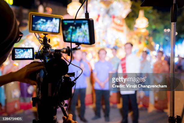 rear of man filming people operating movie camera - film production stock-fotos und bilder